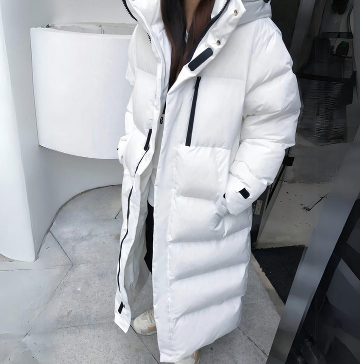 Women's puffer jacket with slanted pockets, zipper, hood, and long fit with thick pockets